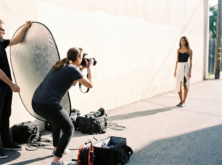 Un tournage de mode en extérieur : photographe, mannequin, réflecteur